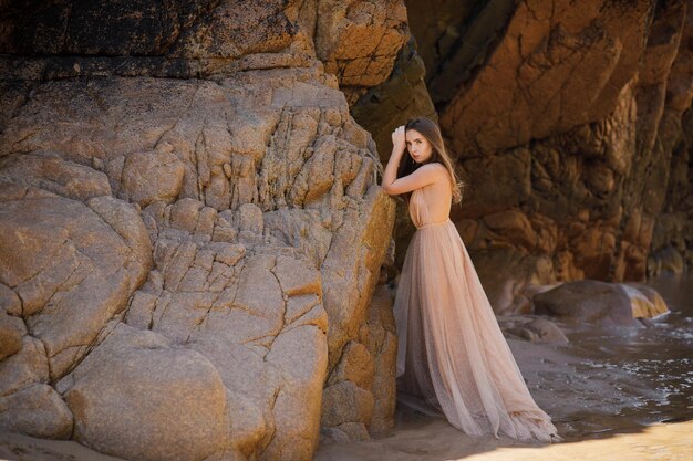 Woman in long dress near rocks and ocean
