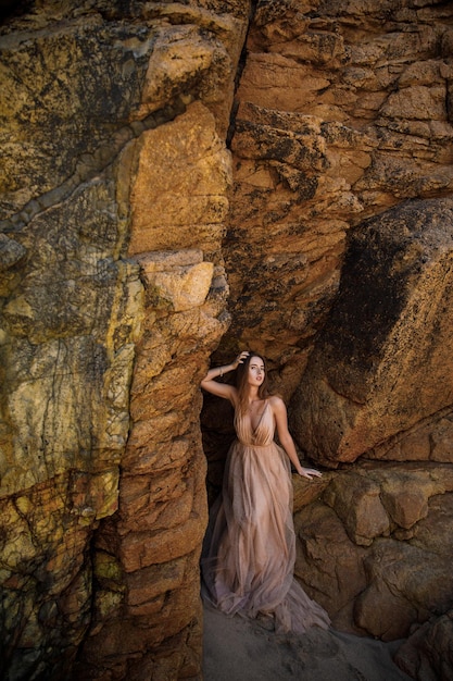 Photo woman in long dress near rocks and ocean