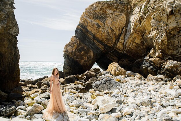 바위와 바다 근처 긴 드레스를 입은 여자