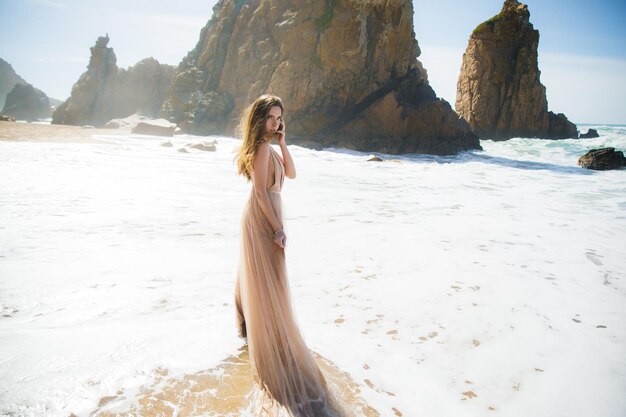 Woman in long dress near rocks and ocean