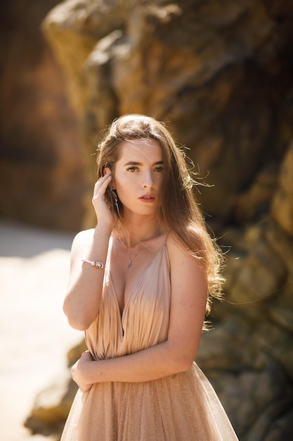 Woman in long dress near rocks and ocean