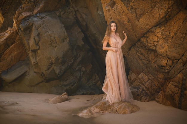 Woman in long dress near rocks and ocean