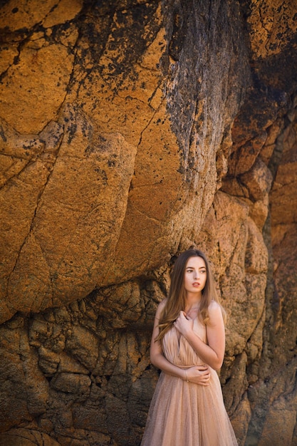 Woman in long dress near rocks and ocean