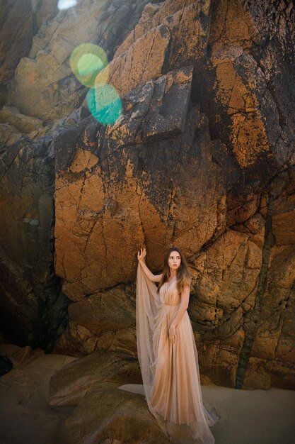 Woman in long dress near rocks and ocean