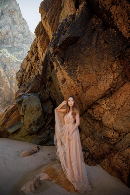 Woman in long dress near rocks and ocean