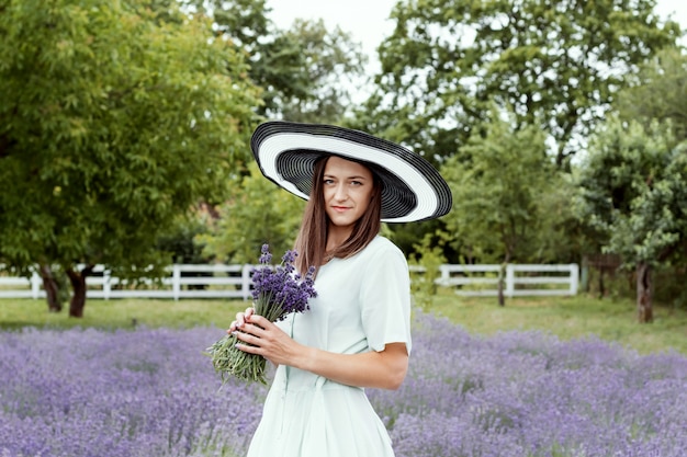 Woman in long olive dress and hat in lavender field 