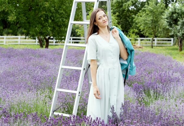 Woman in long olive dress and hat in lavender field 