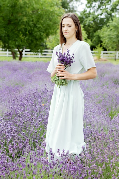 Woman in long olive dress and hat in lavender field 