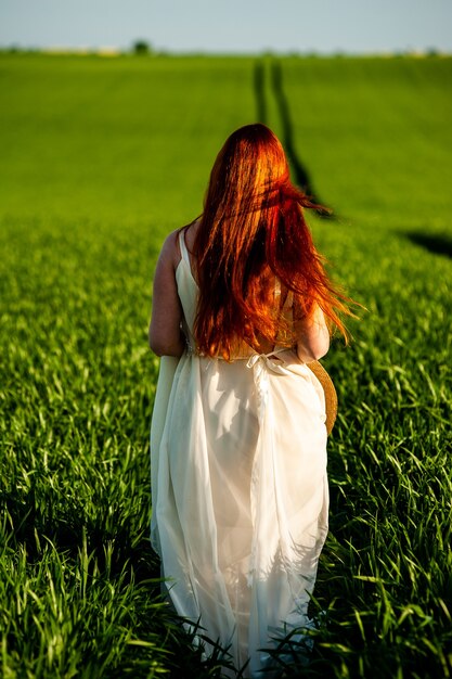 Donna in abito lungo bianco su un campo verde