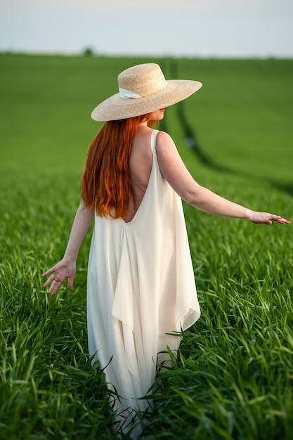 Woman in long white dress on a green field