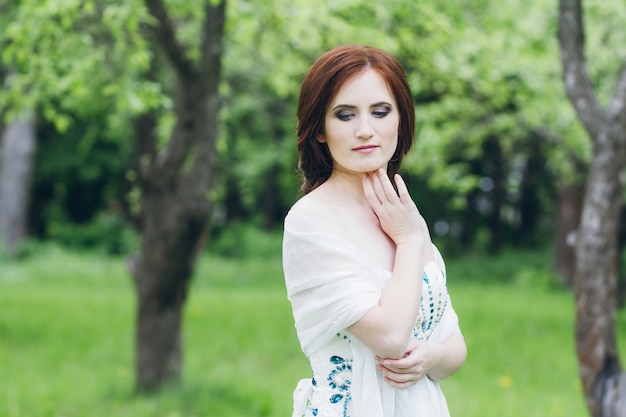 Woman in long white dress in summer garden