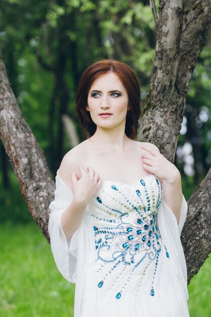 Woman in long white dress in summer garden