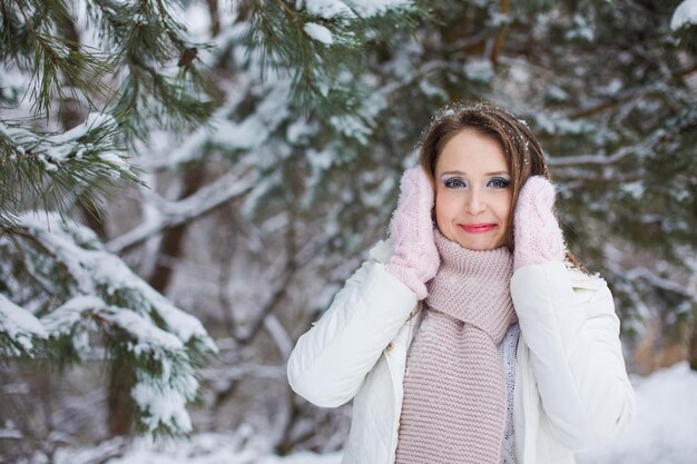 女性が見下ろし、雪に覆われた松の下を何マイルもまつげに雪が降る