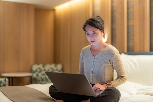 Woman look at the laptop computer and sit on bed