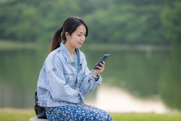 Woman look at mobile phone beside the lake