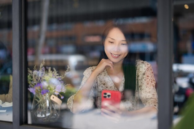 Женщина смотрит на мобильный телефон и сидит внутри кафе