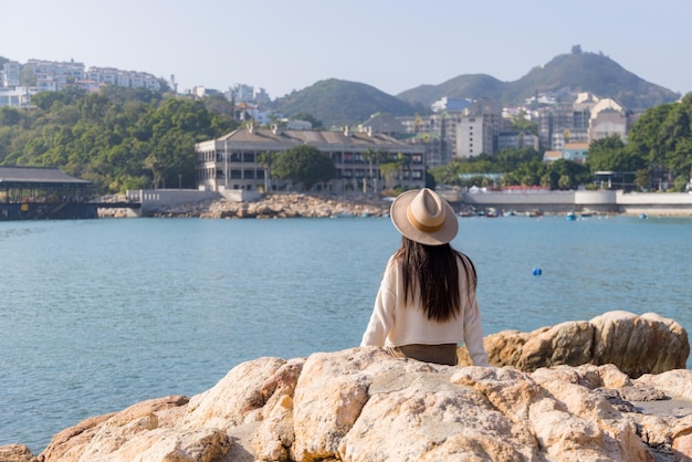 Woman look at the sea and sit on the rock