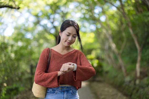 女性は公園でスマートウォッチを見る