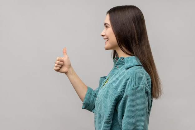 Woman looking ahead with smile and showing thumb up approval sign satisfied with service feedback