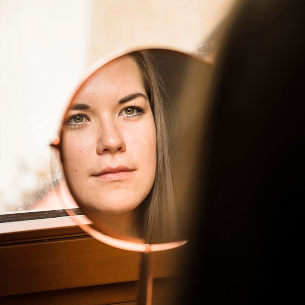 写真 ミラーで彼女の顔を見ている女性