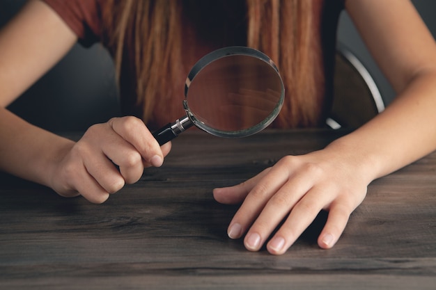 写真 虫眼鏡で自分の爪を見ている女性