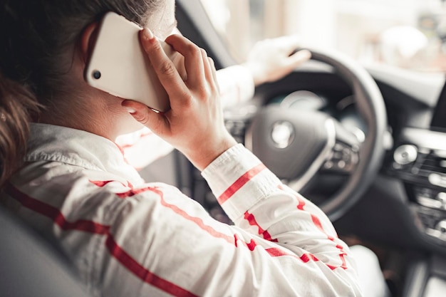 写真 車の運転中に携帯電話を見ている女性 車の中でスマートフォンを使用しているドライバー