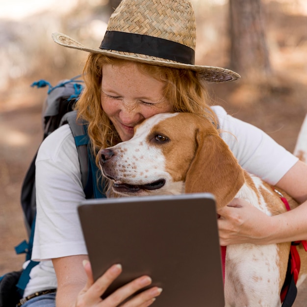 タブレットを見て、犬を抱き締める女性