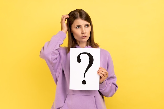 Woman looking away holding paper with question mark thinks about tasks