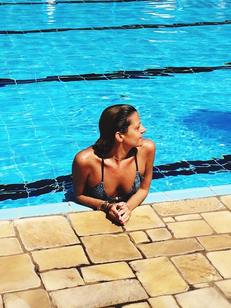 Foto donna che guarda in piscina durante una giornata di sole