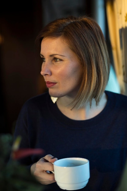 woman looking away while having coffee at cafe