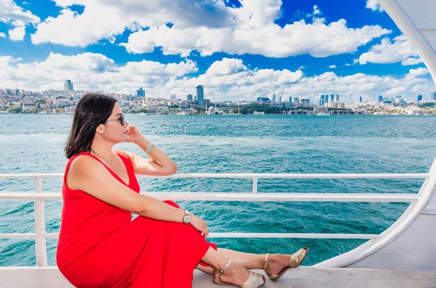 Woman looking away while sitting by railing in nautical vessel on sea