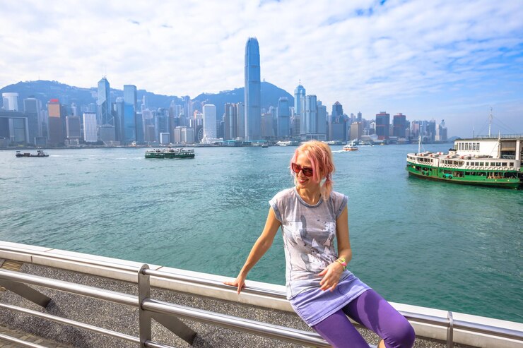 Photo woman looking away while sitting on railing against river in city