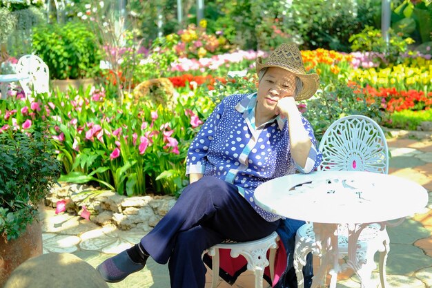 Photo woman looking away while sitting on seat against flowering plants