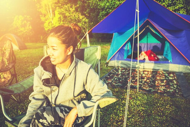 Woman looking away while sitting on seat by tent