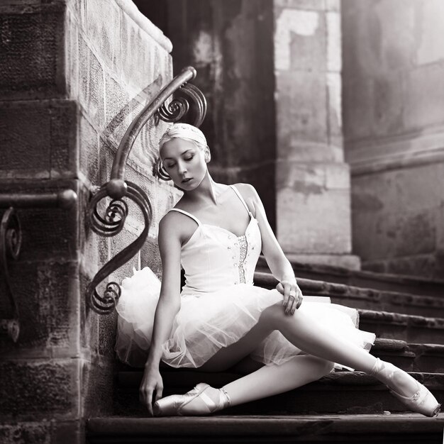 Photo woman looking away while sitting on staircase against building