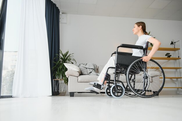 Woman looking away while sitting in wheelchair at home