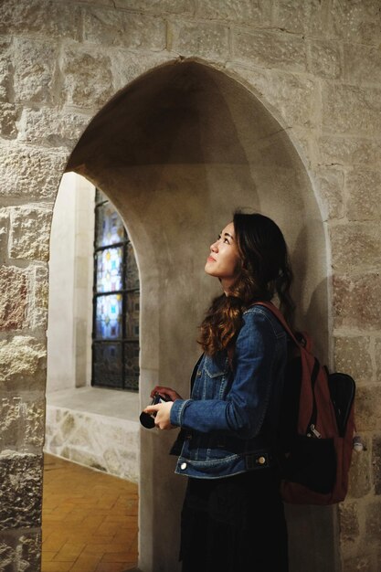 Foto donna che guarda lontano mentre è in piedi contro la finestra