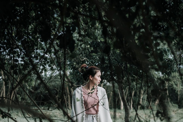 Woman looking away while standing in forest