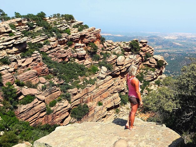 Foto donna che guarda da un'altra parte mentre è in piedi su una roccia