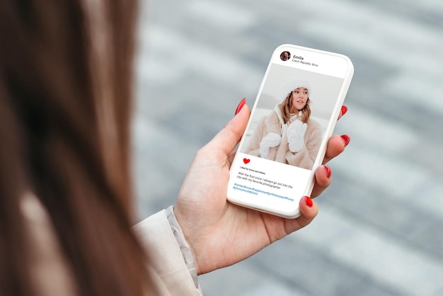 Woman looking at beautiful model's winter photo on mobile phone screen