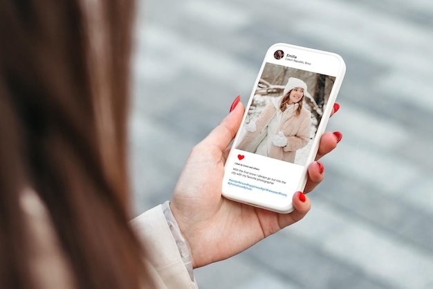 Woman looking at beautiful model's winter photo on mobile phone screen