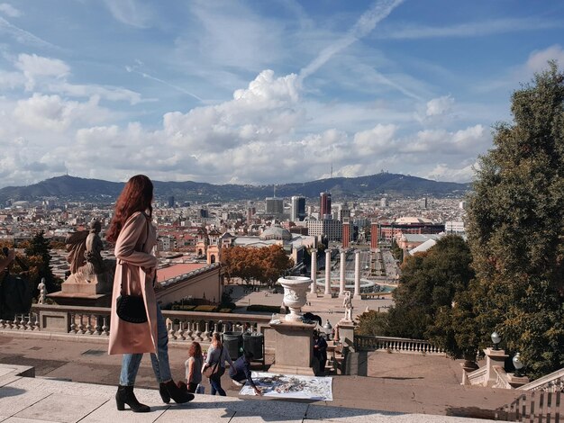 Woman looking at buildings in city against sky