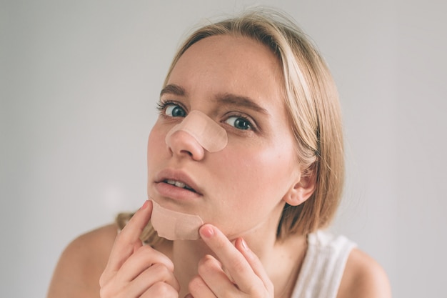 Foto donna che guarda l'obbiettivo che applica l'intonaco sotto il suo occhio