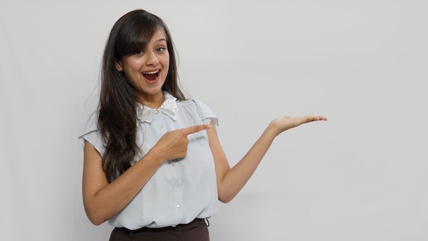 Foto donna che guarda la telecamera che mostra copyspace che punta su sfondo grigio muro