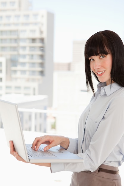 A woman looking at the camera while holding a laptop