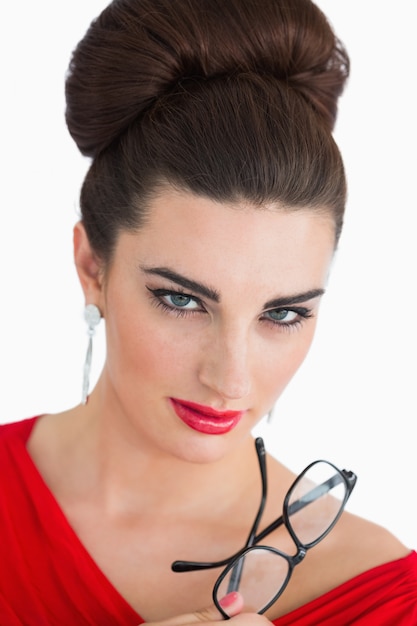 Woman looking at camera while wearing red and holding glasses