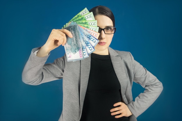 Woman looking at the camera with Kazakhstani money tenge in her hand Covers half of the face with banknotes