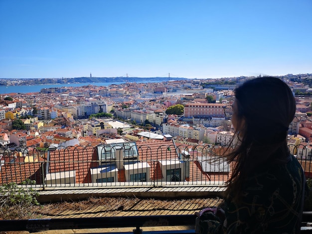 明るい空を背景に都市風景を眺める女性