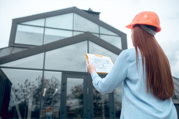 Foto donna che guarda il piano di costruzione e l'edificio