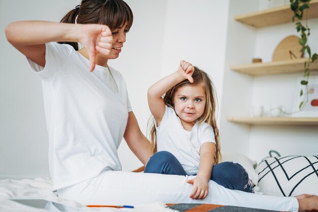 Foto donna che guarda la figlia e mostra i pollici verso il basso